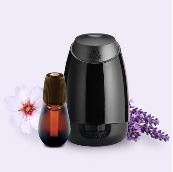 Présente un diffuseur et une recharge Essential Mist® parmi des fleurs de lavande et d’amandes.